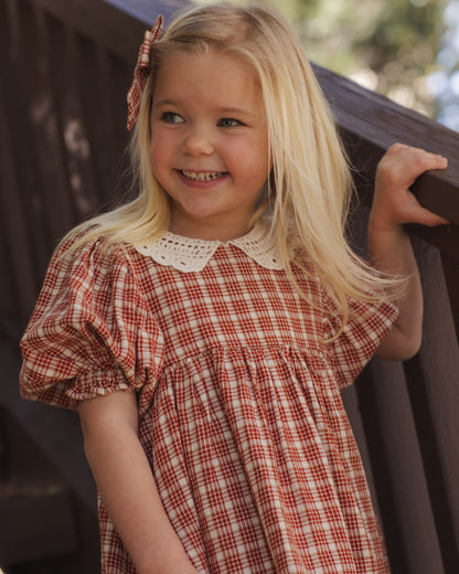 Girl smiling and holding a railing in the Rylee + Cru Heidi dress in red vintage plaid with puff sleeves