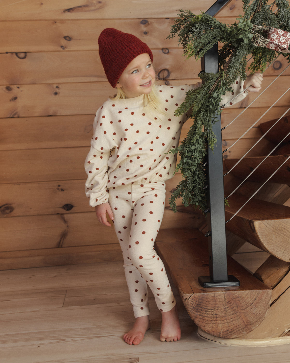 Full-length view of a girl in the Rylee + Cru ruby dots spongey knit set and red beanie on a staircase