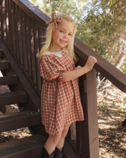 Girl on a wooden staircase outdoors wearing the Rylee + Cru Heidi dress in vintage plaid with a lace collar
