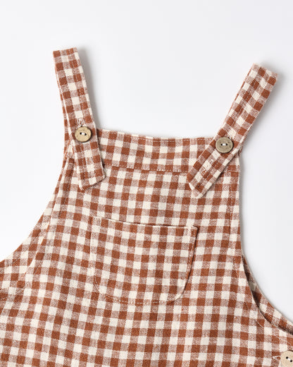 Close view of the brick check overalls showing the bib, straps and wooden buttons