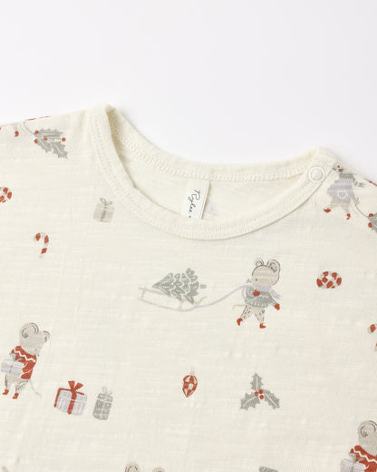 Close-up of a baby long-sleeve top in cream-colored cotton muslin fabric, featuring a festive Christmas print with cartoon mice, gifts, candy canes, and holly in muted red, gray, and green tones.