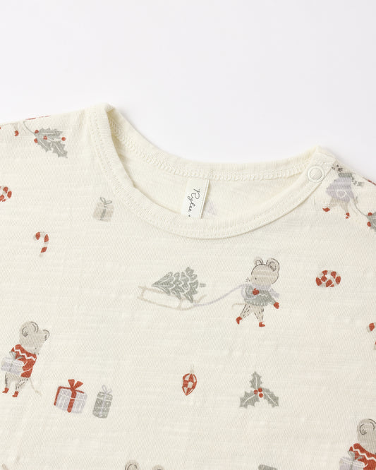 Close-up of a baby long-sleeve top in cream-colored cotton muslin fabric, featuring a festive Christmas print with cartoon mice, gifts, candy canes, and holly in muted red, gray, and green tones.
