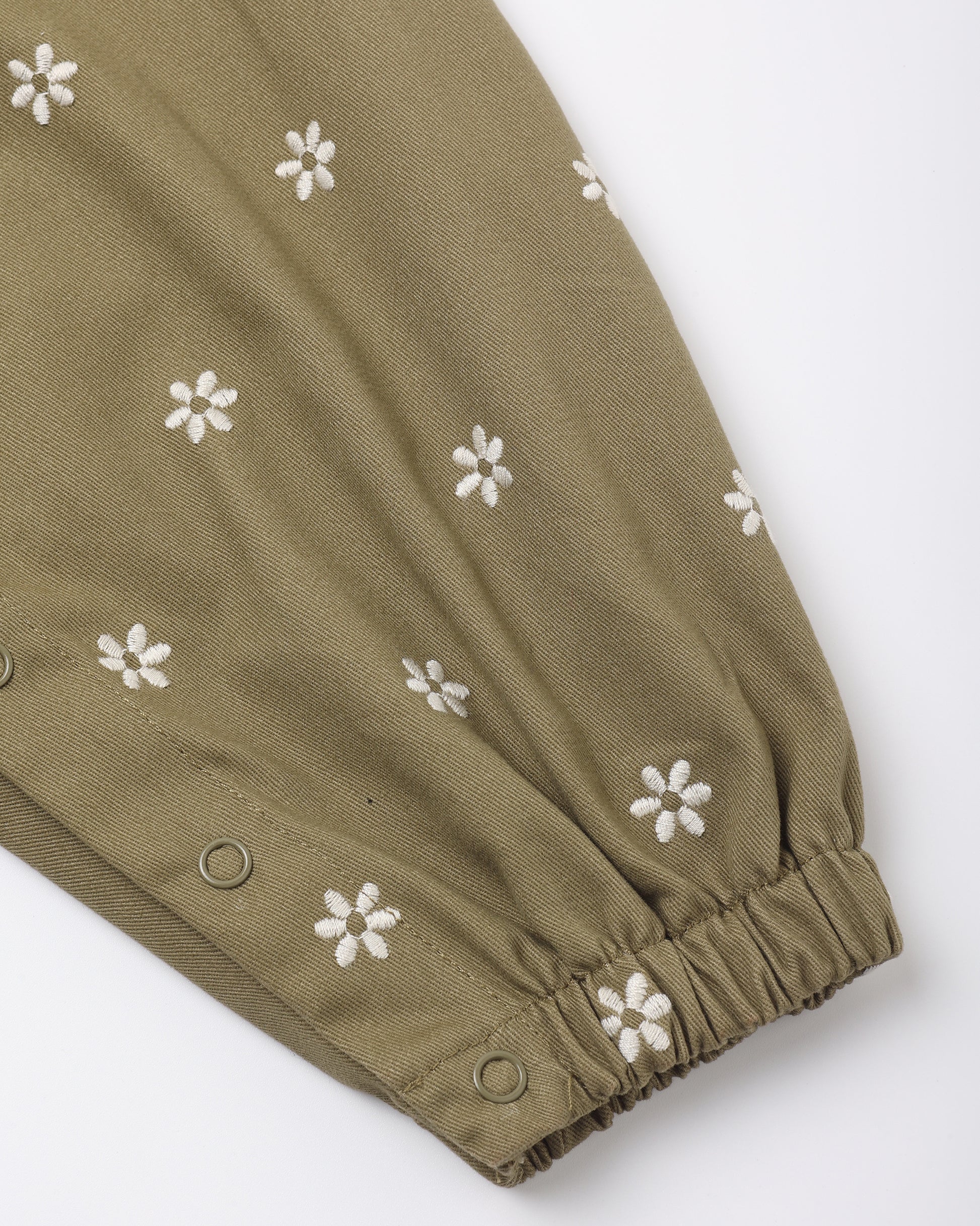 Close view of the embroidered daisies and snap leg opening on the olive Vintage Overall