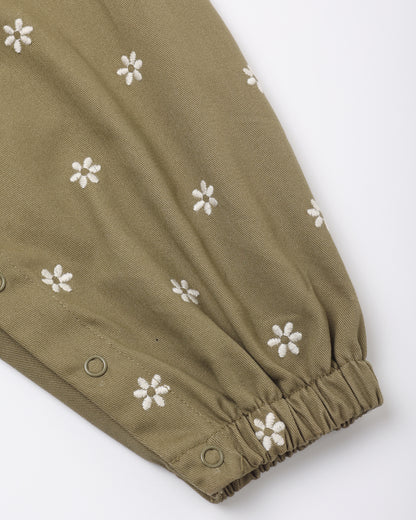 Close view of the embroidered daisies and snap leg opening on the olive Vintage Overall