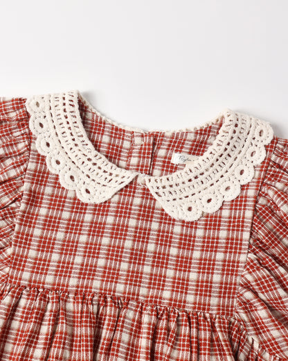 Close-up of a children's dress featuring a red and white gingham pattern with a prominent cream-colored crochet Peter Pan collar.