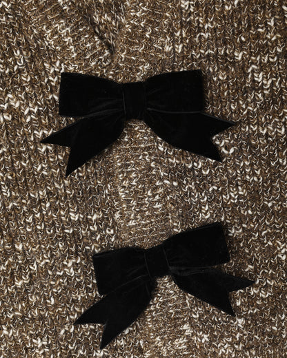 Close view of the black velvet bows stitched onto the heathered stone knit cardigan