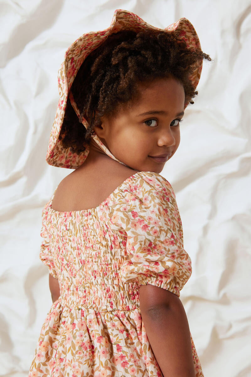 Girl Smiling while wearing Spring Blossom Sun Hat and Spring Blossom Shirred Dress