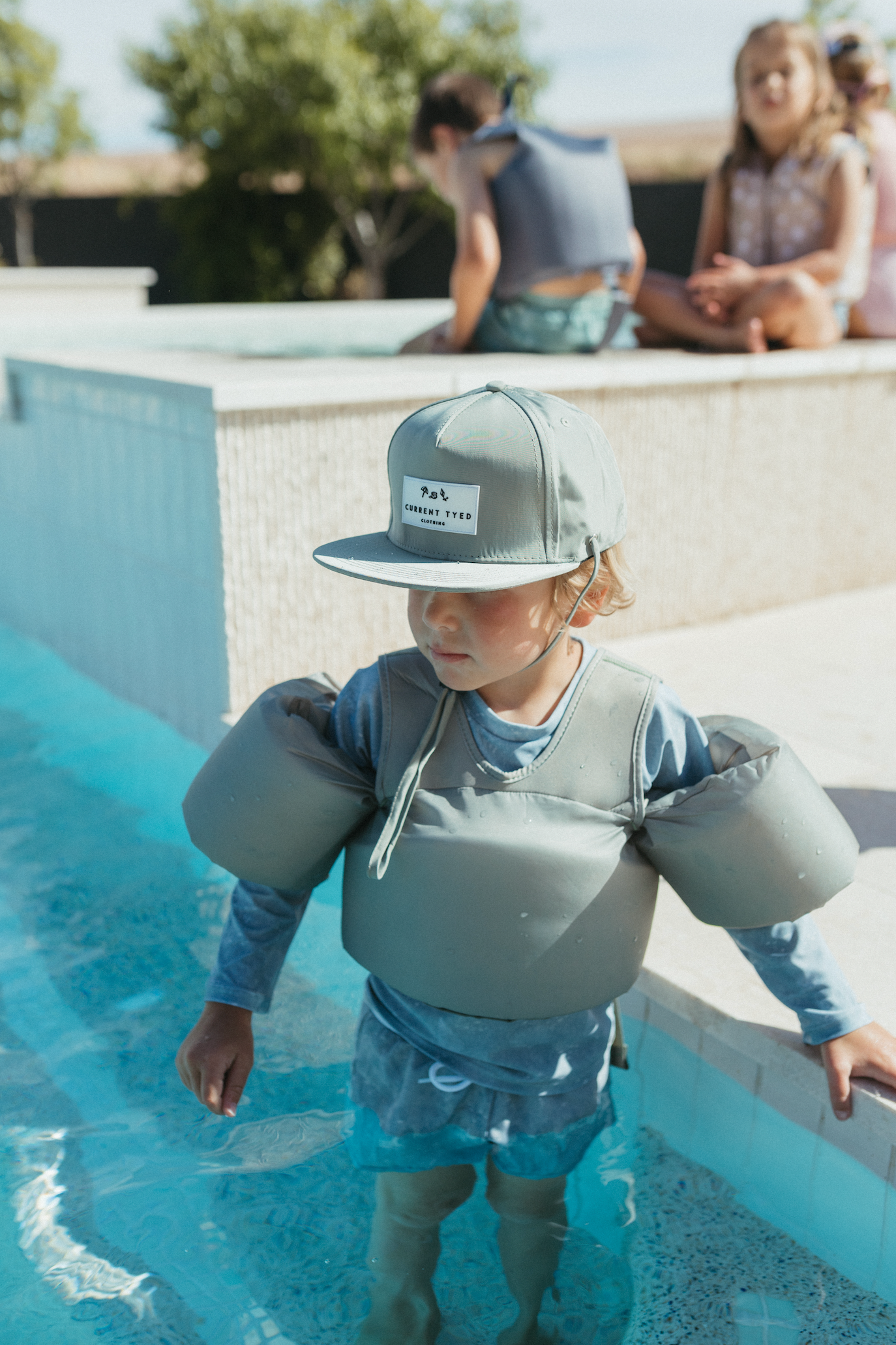 Boy in pool wearing Stone Blue Water Wing Floaties