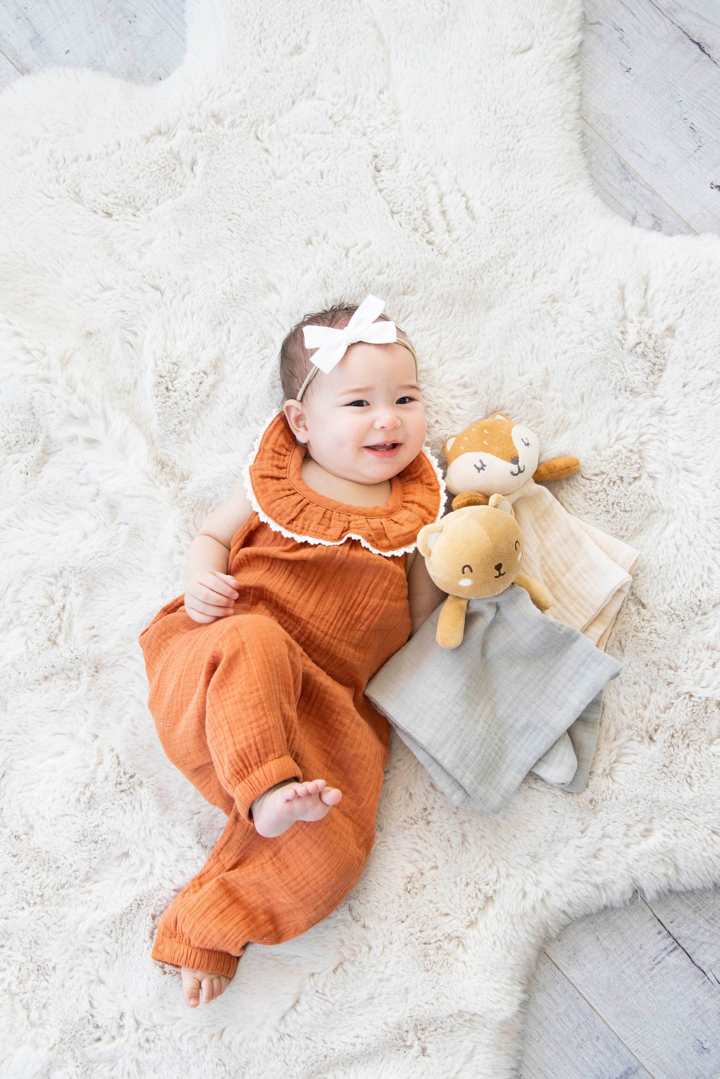 baby girl cuddling with bear snuggle blanket and fox snuggle blanket. 