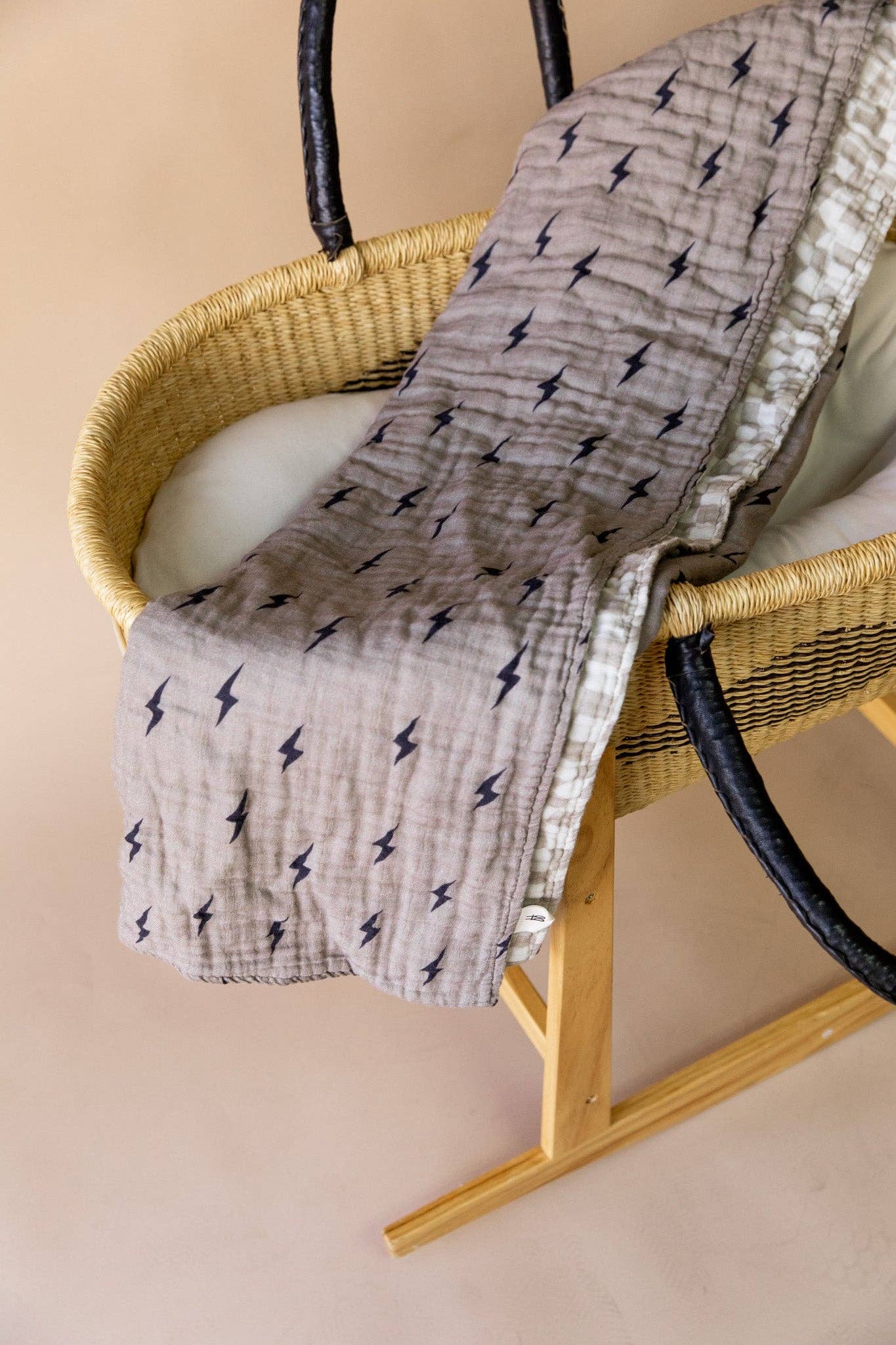Reversible muslin quilt over a woven moses basket, showing the navy lightning bolt print