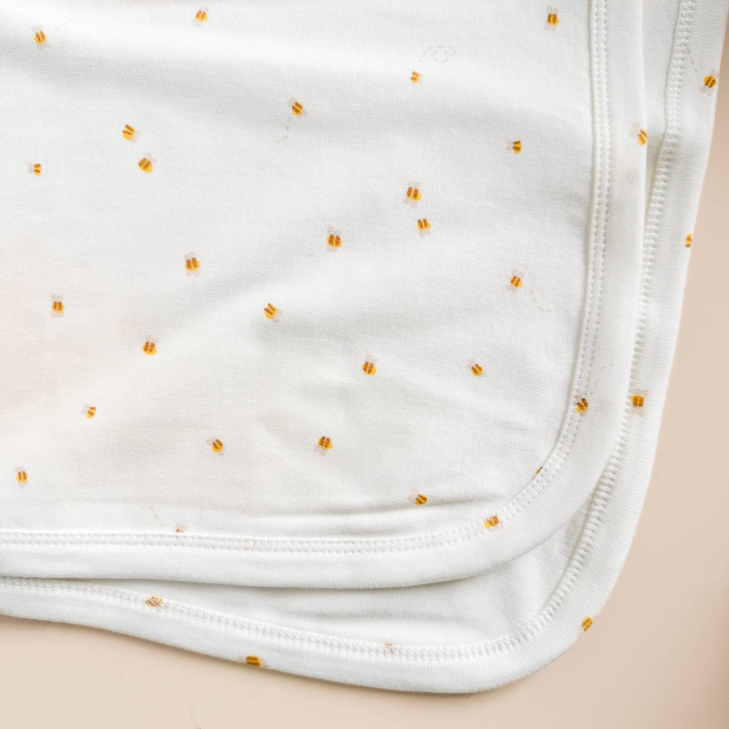 White fabric with small yellow bee pattern on a beige background