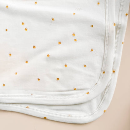 White fabric with small yellow bee pattern on a beige background