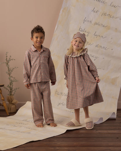 Boy and girl in the Rylee + Cru long sleeve pajamas in holiday gingham standing on a handwritten backdrop