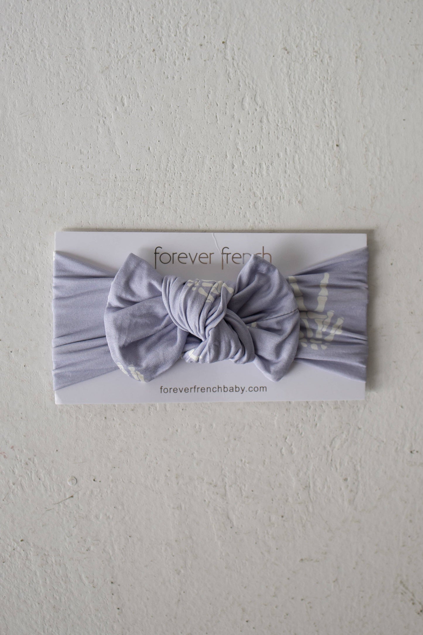Forever French Baby Enchanted Skelly bamboo head wrap in lavender with a bow, shown on its packaging card