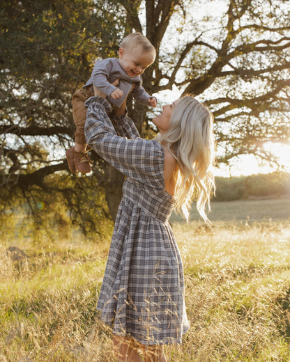 Mother lifting a baby wearing the Rylee + Cru Lucian pant in toffee in a sunlit field