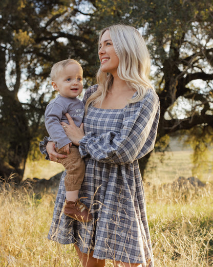 Mother holding a baby in the Rylee + Cru Lucian pant in toffee outdoors under oak trees