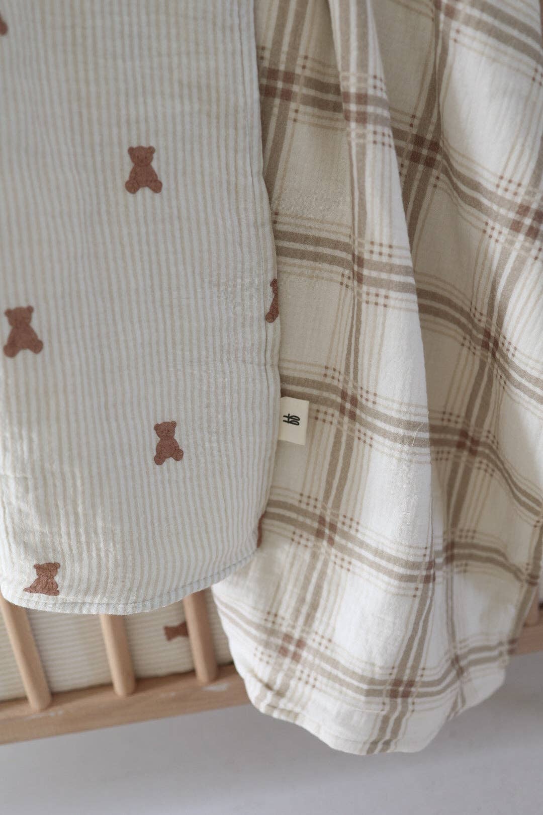 Close view of the reversible muslin quilt: small brown teddy bears on one side, Ellis Plaid windowpane check on the other