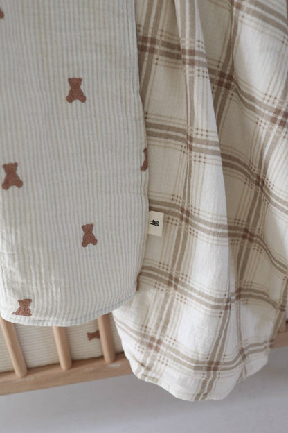 Close view of the reversible muslin quilt: small brown teddy bears on one side, Ellis Plaid windowpane check on the other