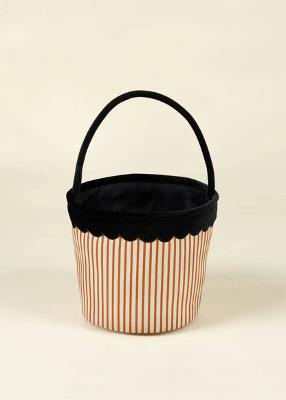 A small fabric storage basket with a black velvet handle and trim, featuring a white body with thin orange vertical stripes, set against a plain cream background.