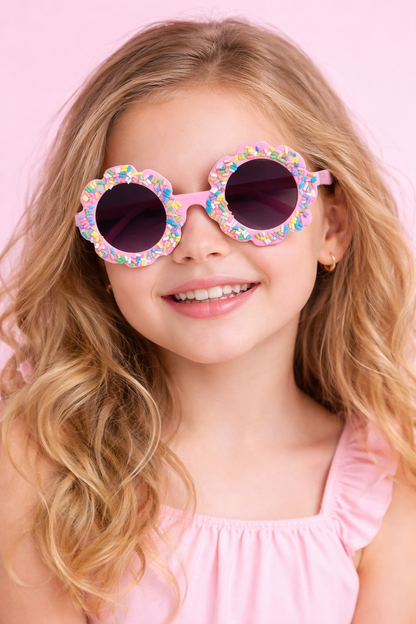 Young girl wearing colorful round sunglasses against a pink background