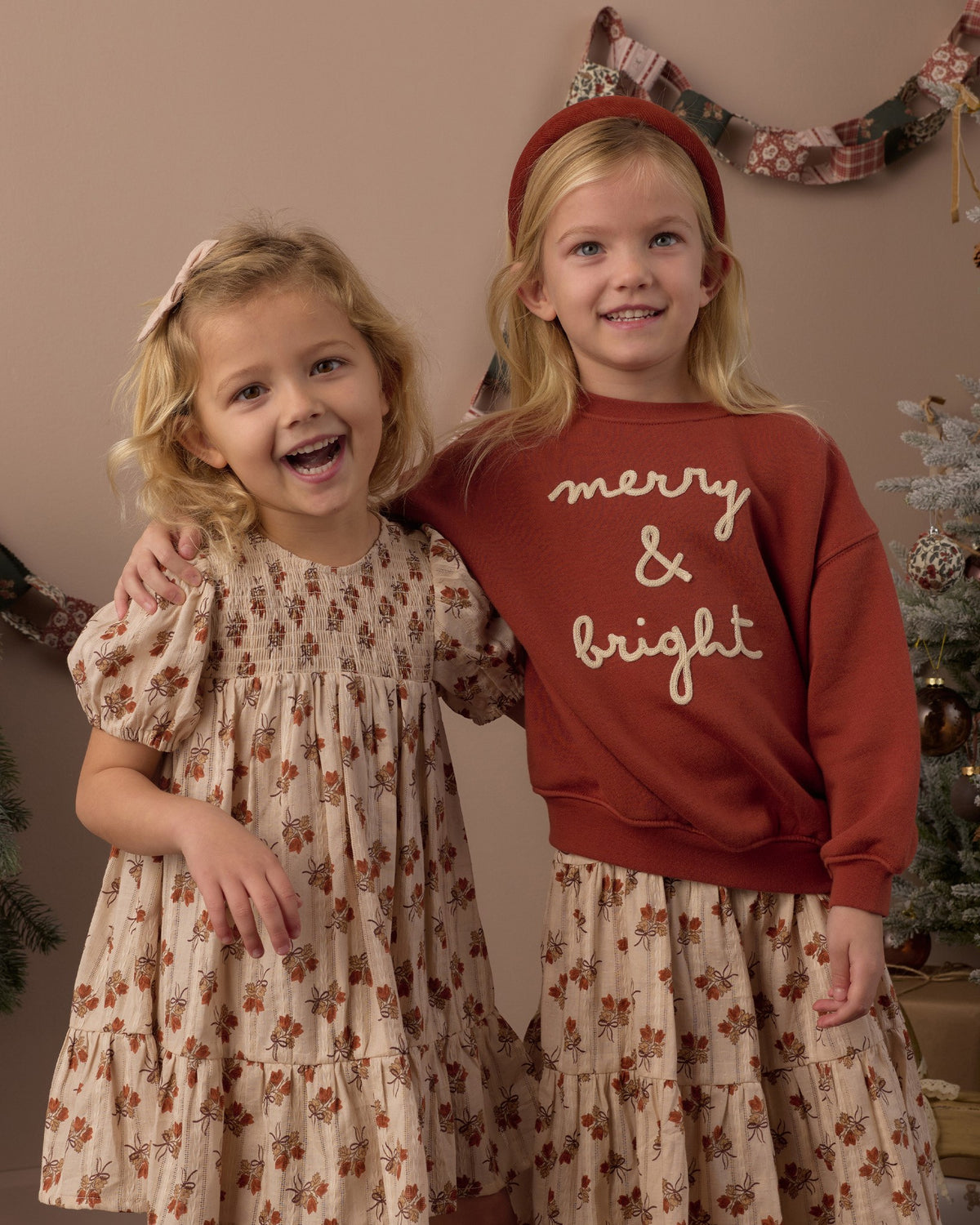 Two girls laughing together, one wearing the Rylee + Cru Merry & Bright relaxed sweatshirt with a floral skirt
