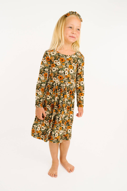 Girl standing in the Little One Shop Rustic Blooms long sleeve bamboo dress in olive floral, front view