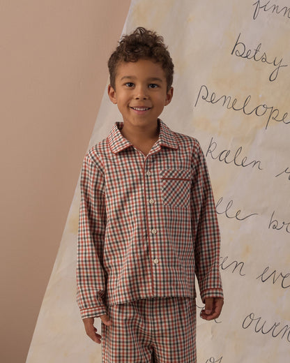 Boy smiling in the Rylee + Cru long sleeve pajamas in holiday gingham, close view of the collar and buttons