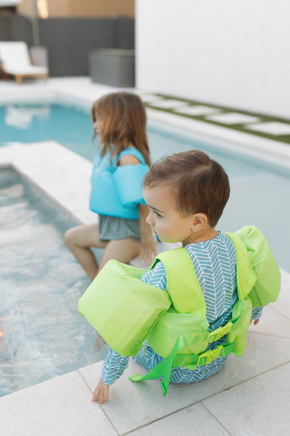 Boy and girl in a pool wearing sea you on top floaties in neon colors