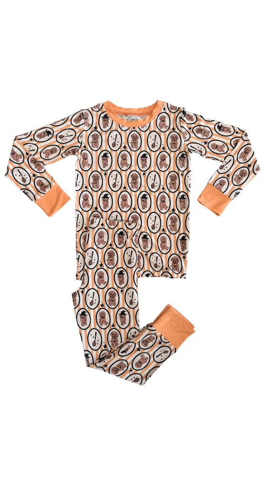 Children's white and orange Halloween pajama set with patterned golden doodle design on a white background