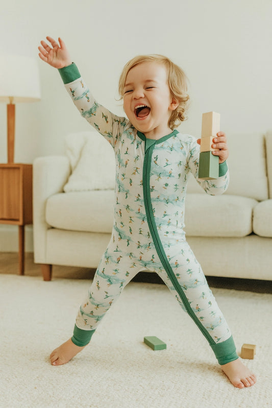 Child in a green and white patterned onesie playing with blocks in a living room.